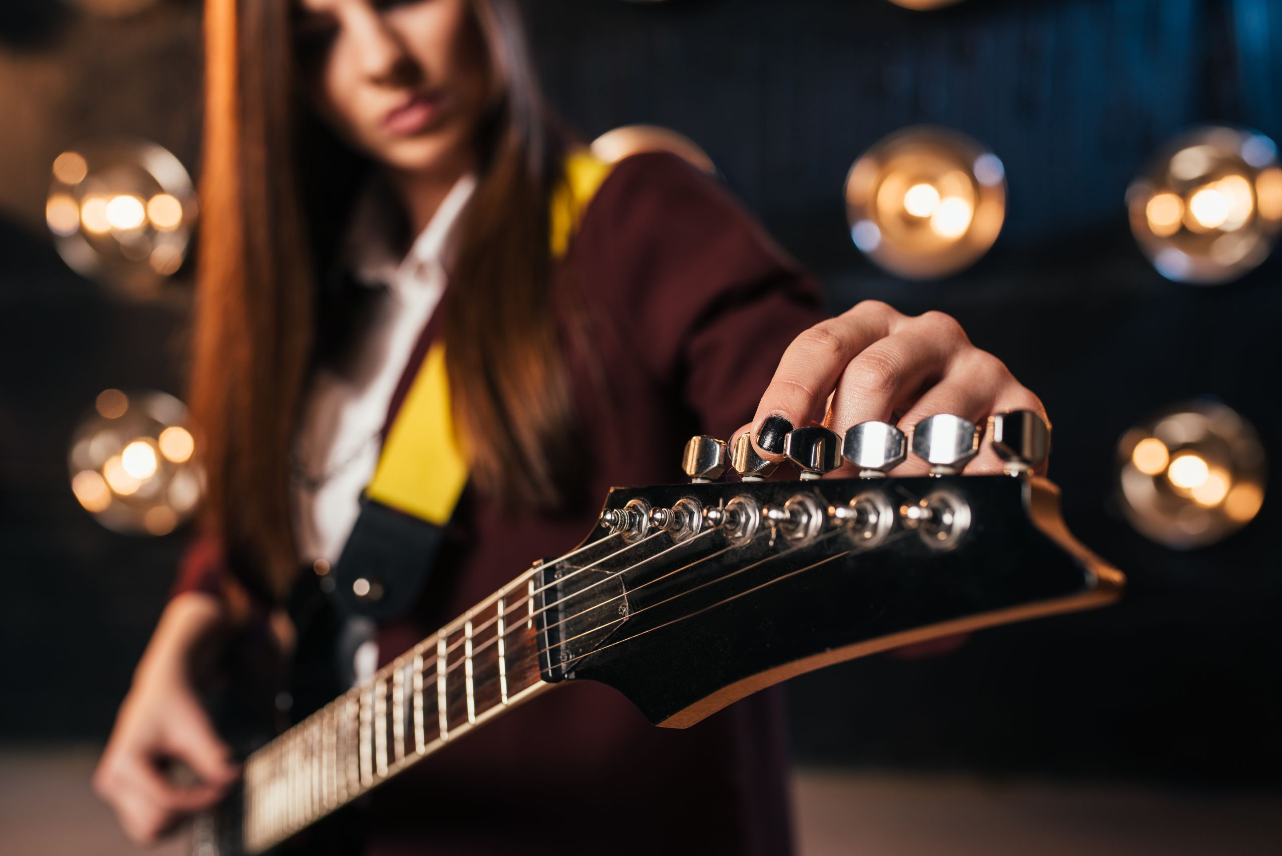 Background image of a musician tuning a guitar